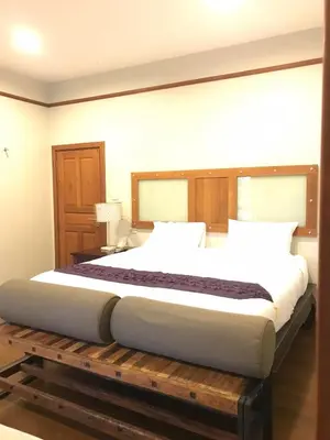 a bedroom with a large bed on a wooden platform at Plumeria Villa Thalang in Ban Pak Lak