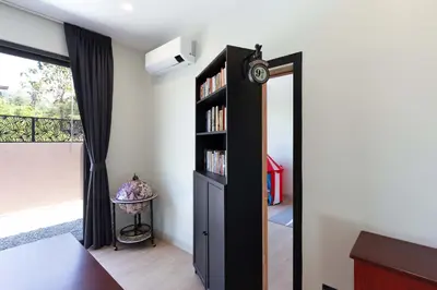 a bedroom with a black book shelf with a clock at Brand-new 8BR Private Pool Villa Mystic Garden in Rawai Beach
