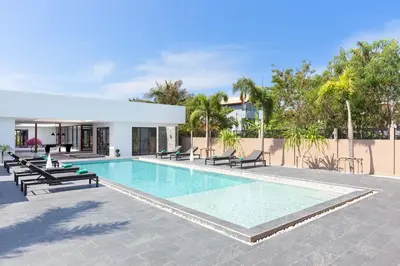 a swimming pool with chaises and chairs next to a building at Brand-new 8BR Private Pool Villa Mystic Garden in Rawai Beach
