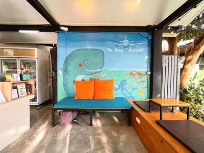 a blue bench with two orange pillows in a room at Sierra Hostel in Nai Yang Beach
