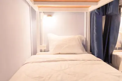 a bed in a small room with blue curtains at Nacha Hostel, Koh Phi Phi, Krabi. THAILAND in Phi Phi Don