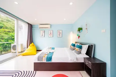 a bedroom with a bed with blue walls and a window at \u82ad\u4e1cVilla1\u4e09\u5367\u53cc\u6d77\u666f\u6cf3\u6c60\u522b\u5885\u4e2d\u82f1\u6cf0\u4e09\u6587\u7ba1\u5bb6 in Patong Beach