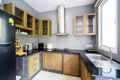 a kitchen with wooden cabinets and a black refrigerator at \u82ad\u4e1cVilla1\u4e09\u5367\u53cc\u6d77\u666f\u6cf3\u6c60\u522b\u5885\u4e2d\u82f1\u6cf0\u4e09\u6587\u7ba1\u5bb6 in Patong Beach