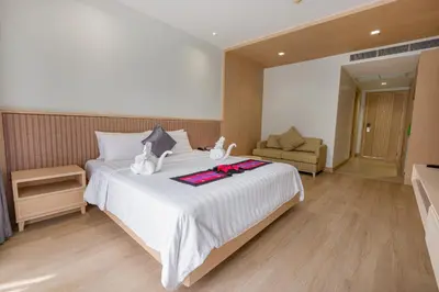 a bedroom with a large white bed and a chair at Estella Phuket Mai Khao Beach Resort in Mai Khao Beach