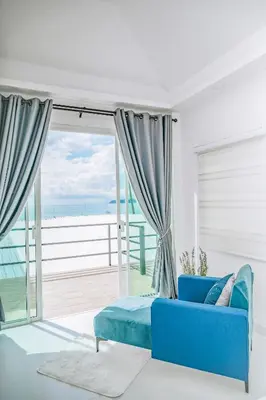 a blue couch in a living room with a view of the ocean at Mr Oh's Seaview House Phuket AoYon in Phuket Town