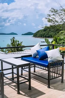 a bench with blue and white pillows on a deck at Mr Oh's Seaview House Phuket AoYon in Phuket Town