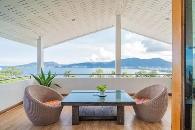 a room with a table and chairs and a view of the ocean at Patong Blue House Panorama View in Patong Beach