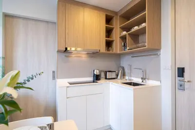 a kitchen with white counters and wooden cabinets at SkyPark , Bangtao , Apartment near beach 2 bedroom in Bang Tao Beach