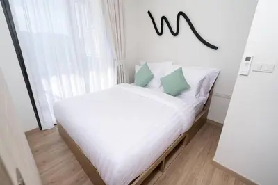 a bed with white sheets and green pillows in a room at SkyPark , Bangtao , Apartment near beach 2 bedroom in Bang Tao Beach
