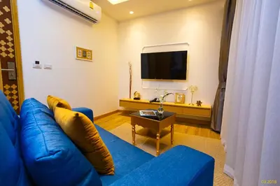 a living room with a blue couch and a tv at Aristo 2 Apartments by Beringela in Surin Beach