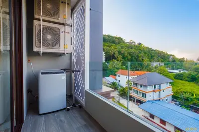 a balcony with a refrigerator and a view of a house at Aristo 2 Apartments by Beringela in Surin Beach