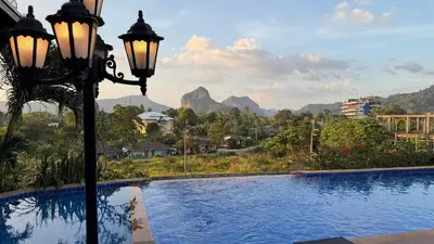 a pool with a street light and mountains in the background at Phu Dahla Apartments in Ban Khlong Haeng