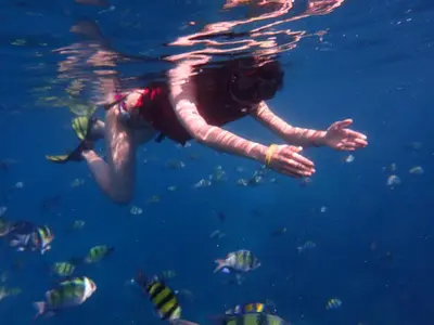 a person swimming in the water with fish at Kana Hotel Phuket\u666e\u5409\u5c9b\u5361\u5a1c\u9152\u5e97 in Rawai Beach