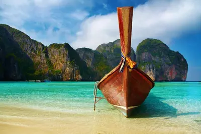 a boat sitting on a beach in the water at Kana Hotel Phuket\u666e\u5409\u5c9b\u5361\u5a1c\u9152\u5e97 in Rawai Beach