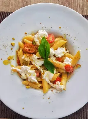 a plate of pasta with cheese and a green garnishment at Lo Sfizio in Patong Beach