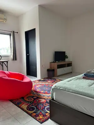 a bedroom with a bed and a red chair on a rug at Lo Sfizio in Patong Beach