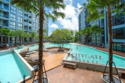 an indoor swimming pool with palm trees and buildings at Citygate Peaceful Condo Kamala Beach in Kamala Beach