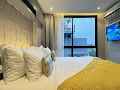 a bedroom with a bed with white pillows and a tv at Citygate Peaceful Condo Kamala Beach in Kamala Beach