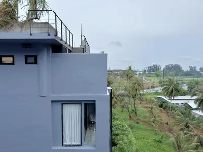 a white house with a balcony and palm trees at Citygate Peaceful Condo Kamala Beach in Kamala Beach