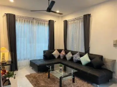 a living room with a black leather couch with pillows at Kata Sea Blue Villa in Kata Beach