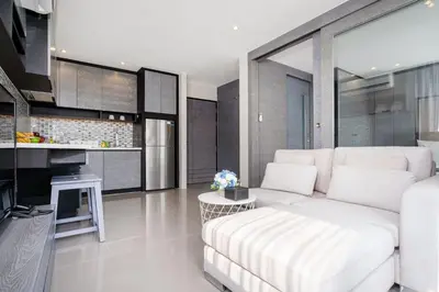 a living room with a white couch and a kitchen at Tropics Kamala Hill View Suite CTG P614, near Beach and Fantasea in Kamala Beach