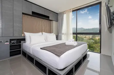 a bedroom with a large bed with a large window at Tropics Kamala Hill View Suite CTG P614, near Beach and Fantasea in Kamala Beach