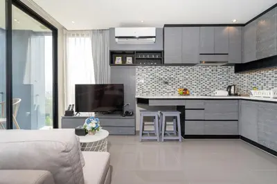 a living room with a kitchen with a couch and a tv at tropics Kamala CTG L604, near FantaSea & Café Del Mar Beach Club in Kamala Beach