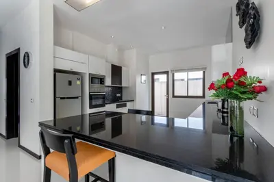 a kitchen with a black counter and a vase of red roses at \u3010\u8d85\u503c\u30112\u5367\u5ba4\u522b\u5885\u3010\u5bbd\u655e\u8212\u9002\u301113\u7c73\u957f\u79c1\u5bb6\u6cf3\u6c60\uff0c\u914d\u5957\u9f50\u5168\u51fa\u884c\u65b9\u4fbf\uff0c\u6b65\u884c700\u7c73\u5230kamala\u6d77\u6ee9 V03 in Kamala Beach