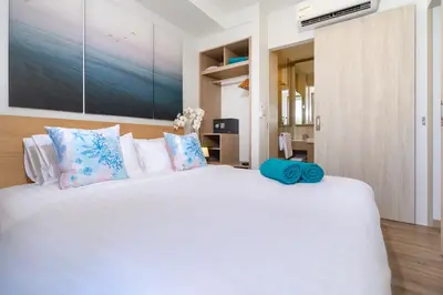 a bedroom with a large white bed with blue pillows at SkyPark Bangtao, Laguna 2 bedroom apartment 5 minutes from the beach in Phuket Town