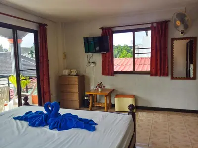 a bedroom with a bed with blue sheets and a window at Kata Lina guesthouse in Kata Beach