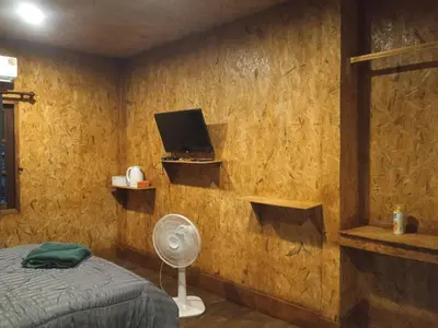 a bedroom with a bed and a tv and a fan at Sukanyawoodhouse in Ban Tha Rua