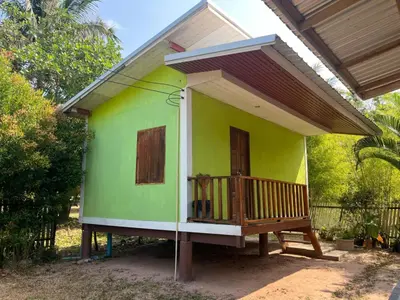 a small green and white house with a porch at Sukanyawoodhouse in Ban Tha Rua