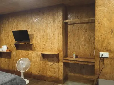 a bedroom with a bed and a tv on a wall at Sukanyawoodhouse in Ban Tha Rua
