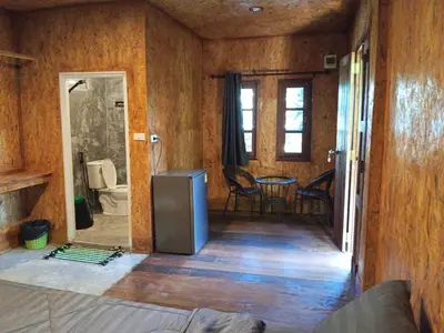 a room with a kitchen and a table with chairs at Sukanyawoodhouse in Ban Tha Rua