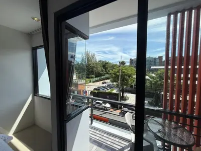 a room with a balcony with a view of a street at Jhen House in Nai Yang Beach