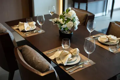 a wooden table with glasses and a vase of flowers at ANGSANA Oceanview apartments with jacuzzi in Laguna area in Bang Tao Beach