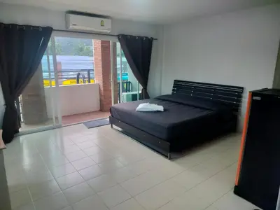 a bedroom with a black bed and a large window at the three pyramids in Rawai Beach