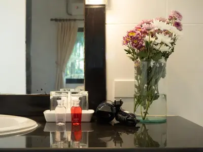 a bathroom counter with a vase of flowers and a mirror at Isara Nai Yang resort in Nai Yang Beach