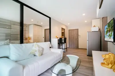 a living room with a white couch and a kitchen at F12 Номер Люкс Бассейн Рубль ВАТСАП669З582I976 in Nai Yang Beach