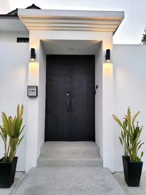 a black door on a white house with two plants at Villa Coco - Tropical Paradise with Private Pool in Thalang