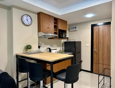 a kitchen with a table and a clock on the wall at 1bdr Pool Access Apartment Rawai Beach Condominium by Capital Pro in Phuket Town