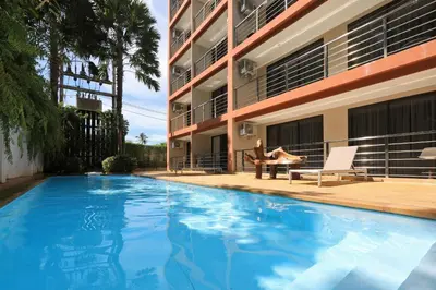 a woman sitting in a chair next to a swimming pool at 1bdr Pool Access Apartment Rawai Beach Condominium by Capital Pro in Phuket Town