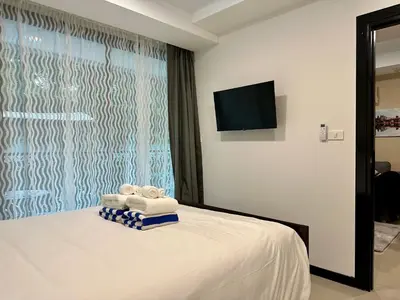 a bedroom with a bed with towels and a television at 1bdr Pool Access Apartment Rawai Beach Condominium by Capital Pro in Phuket Town