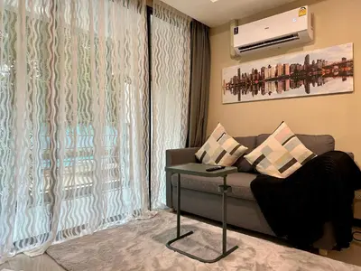 a living room with a couch and a window at 1bdr Pool Access Apartment Rawai Beach Condominium by Capital Pro in Phuket Town