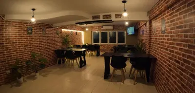 a restaurant with tables and chairs against a brick wall at KPOP Hostel in Karon Beach