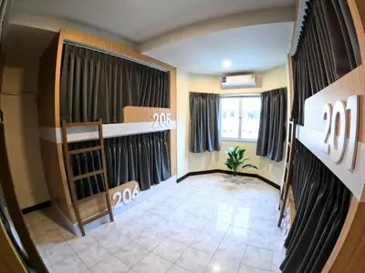 an empty room with a bed and a window at KPOP Hostel in Karon Beach