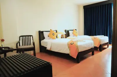 a bedroom with two beds and a chair at Harmony Patong Hotel in Patong Beach