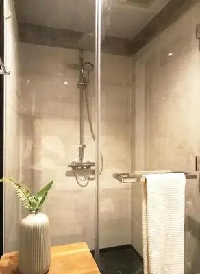 a bathroom with a shower with a vase on a table at Waterfront Suites Phuket by Centara NEW in Phuket Town