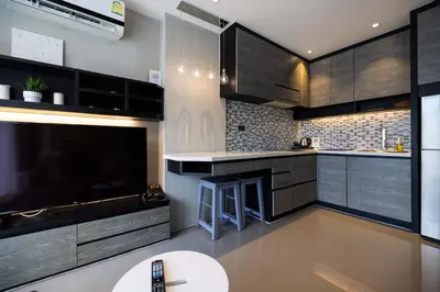 a kitchen with dark wood cabinets and a tv at Modern Condo in Boutique Style Resort CGB4 in Phuket Town