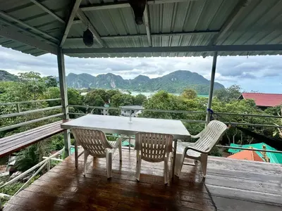 a table and chairs on a deck with mountains in the background at Hilltop view - Phi Phi in Phi Phi Don